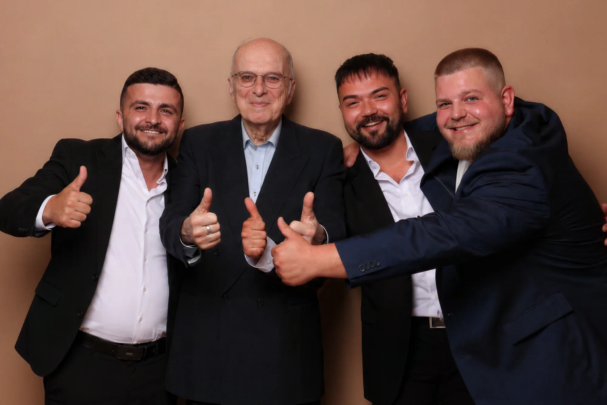Das Team 2026 mit Peter Giesecke: vier Männer im Anzug, alle mit Daumen hoch und bester Laune